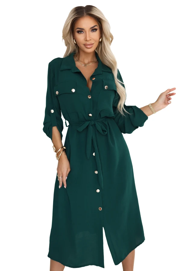 Modelka prezentuje zieloną szmizjerkę midi z paskiem w talii, guzikami i kieszeniami na piersiach – elegancka sukienka Numoco Basic, produkcja europejska.