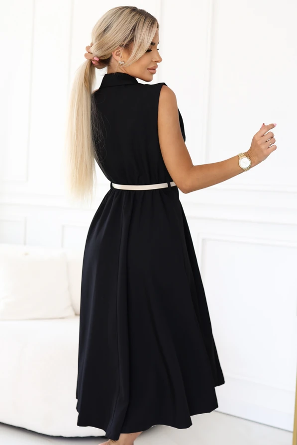 Modelka prezentuje czarną elegancką sukienkę midi bez rękawów z ozdobnymi guzikami i beżowym paskiem w talii od Numoco Basic, stojąc w jasnym, nowoczesnym wnętrzu. Stylowa, klasyczna propozycja idealna na lato, spotkania i codzienne stylizacje.