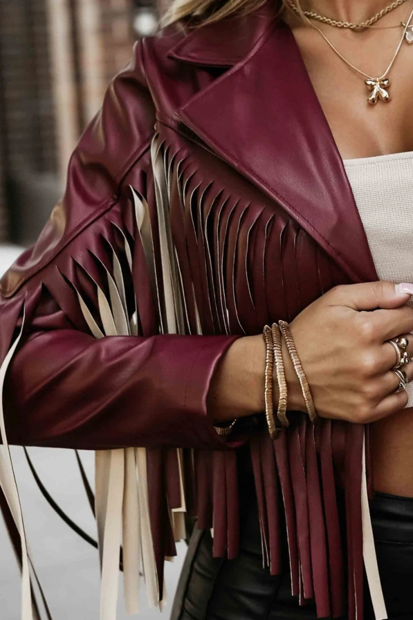 Modelka prezentuje burgundową ramoneskę z frędzlami wykonaną z ekoskóry, idealną do stylizacji w klimacie boho i rock chic.